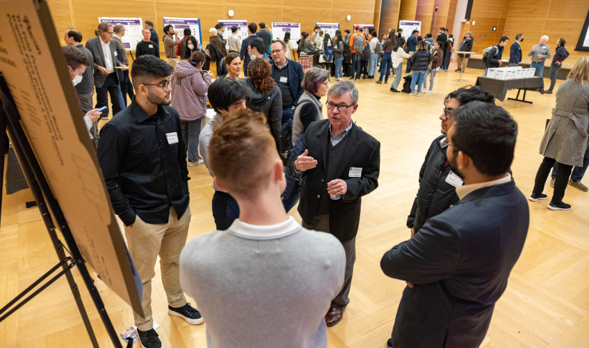 Audience member asking questions to EIH students in front of poster