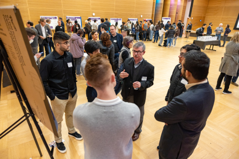 Audience member asking questions to EIH students in front of poster