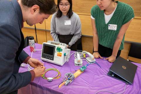 Members of the Currently team demonstrate their research to a visitor during the annual EIH Spring Symposium.